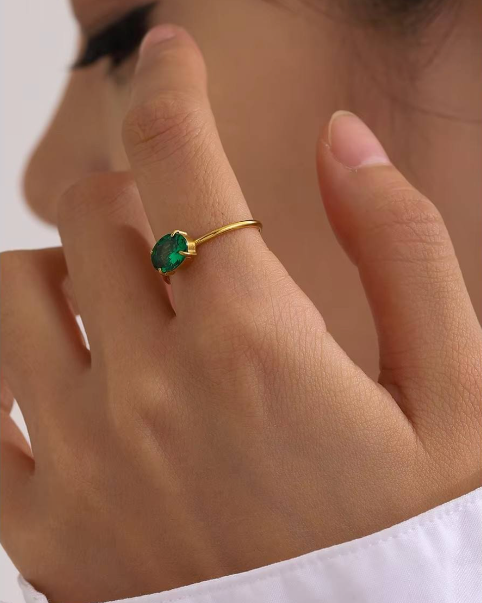 Gold ring with a green gemstone on a person's finger