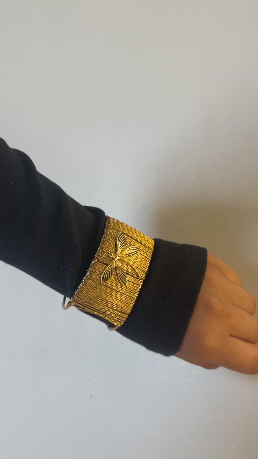 Gold bracelet with a butterfly design on a white background