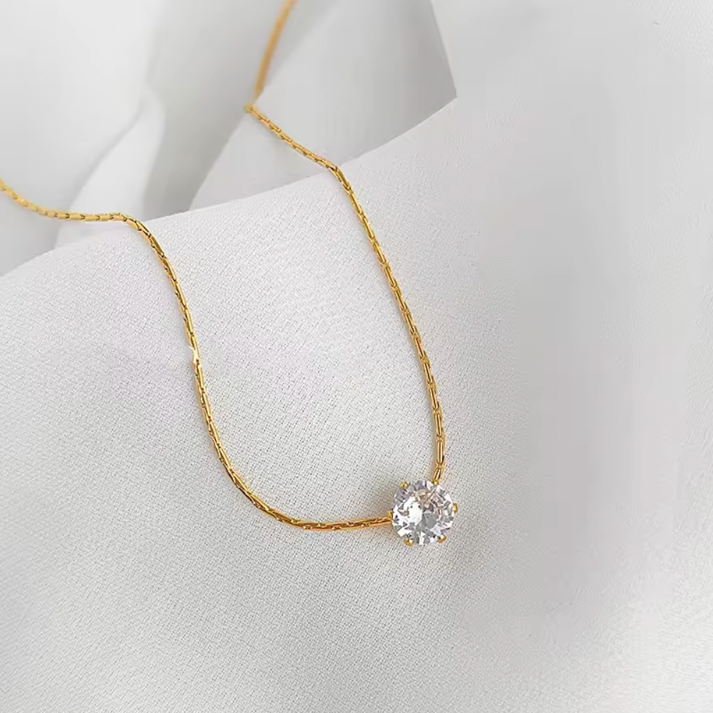Gold necklace with a diamond pendant on a white background