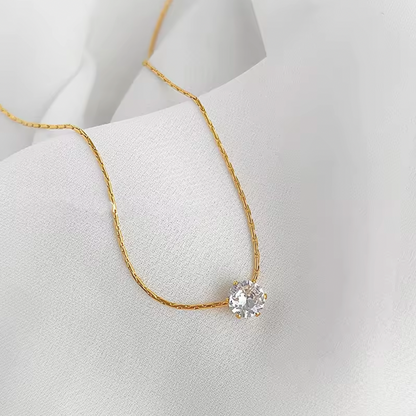 Gold necklace with a diamond pendant on a white background